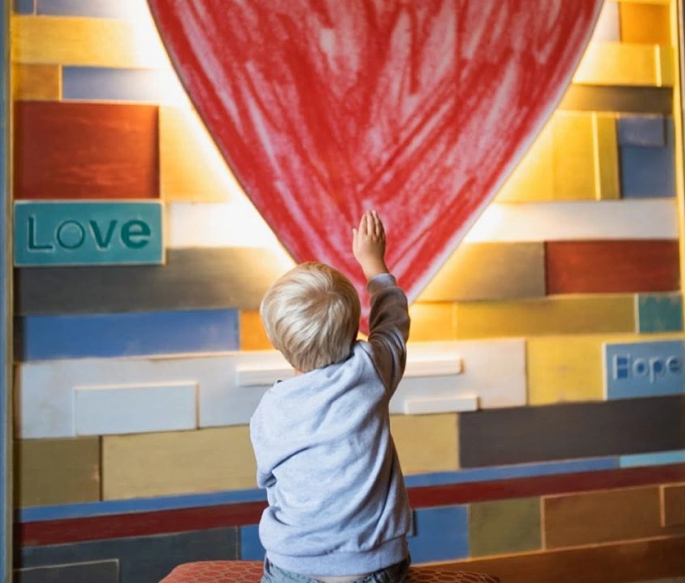 little boy sitting with his back to the camera pointing at a heart
