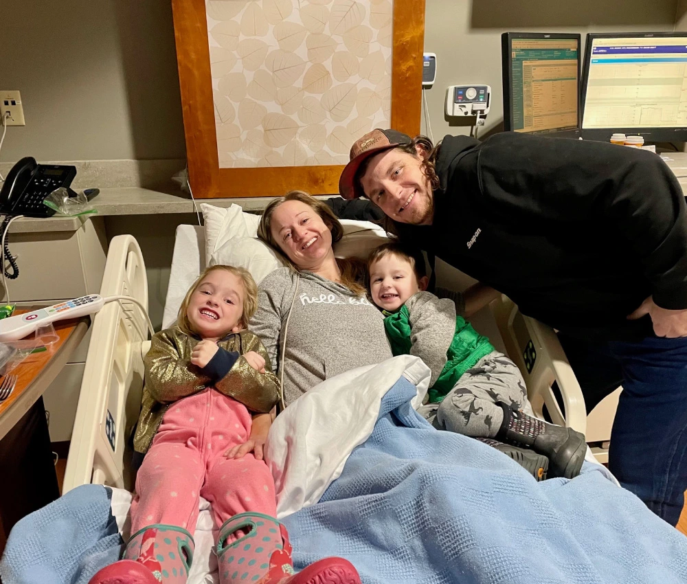Bentley family with mother father and two little children sitting on hospital bed