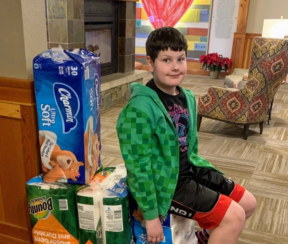 pre-teenage boy with a large donation of paper towels and toilet paper for our house