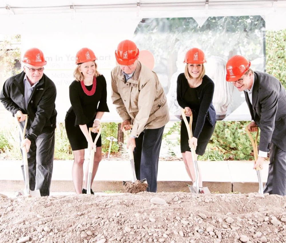 Board Members in red hard hats breaking ground on new facility
