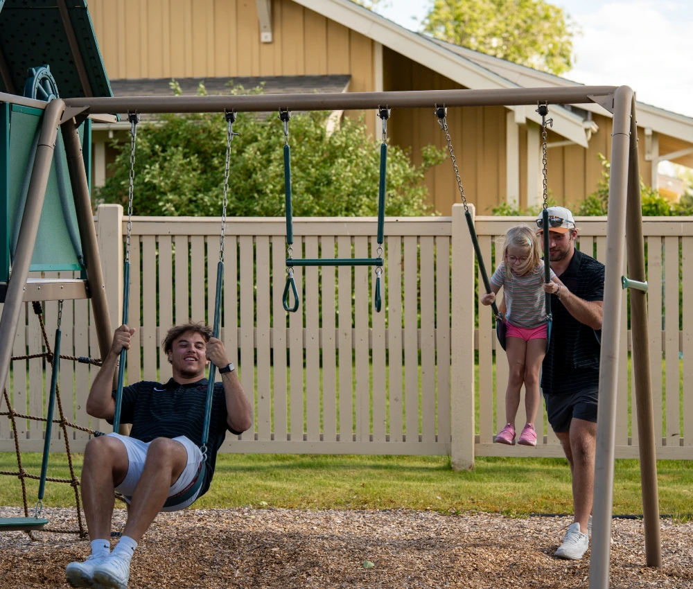 two football players with a little girl on the swings