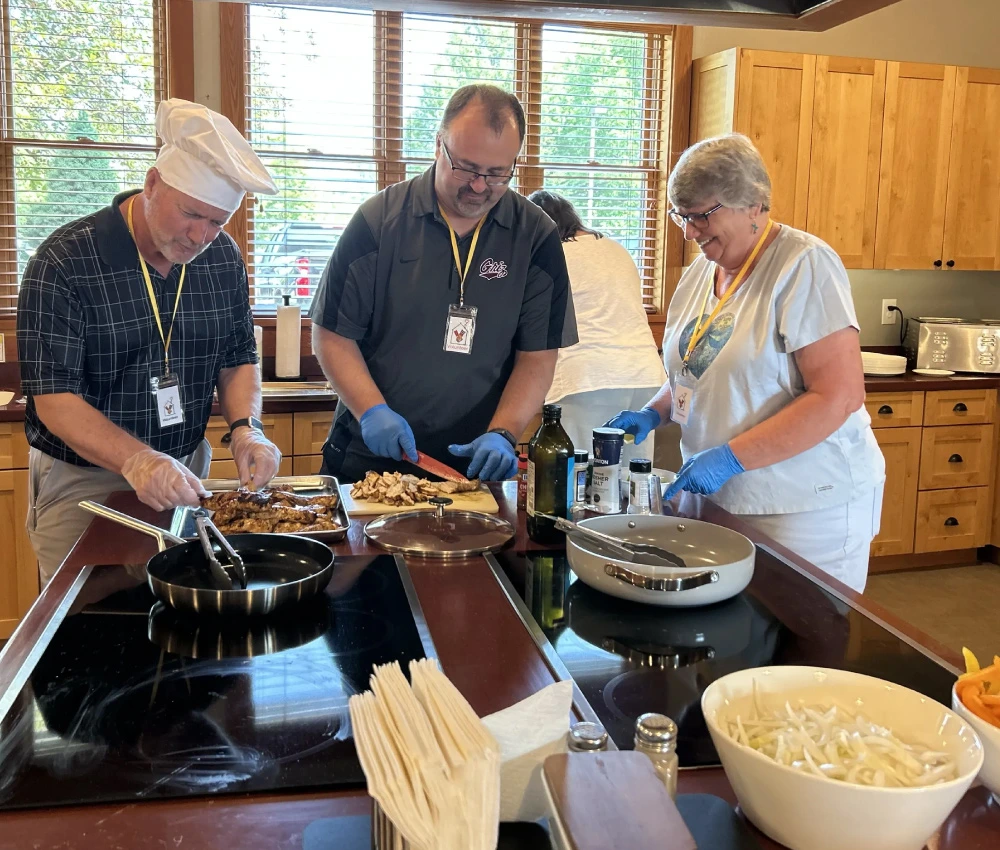 group of three volunteers working to prepare a meal for our families