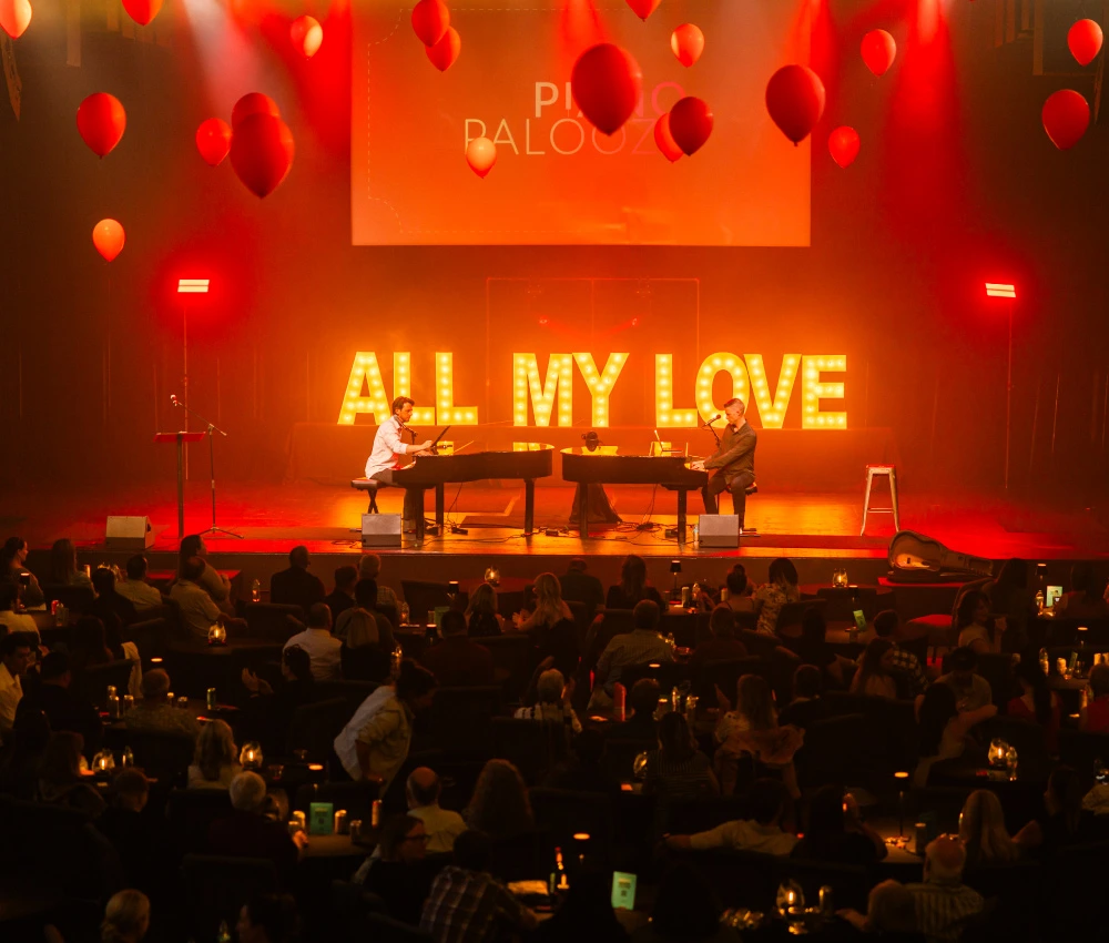 dueling pianists on stage in front of a large audience
