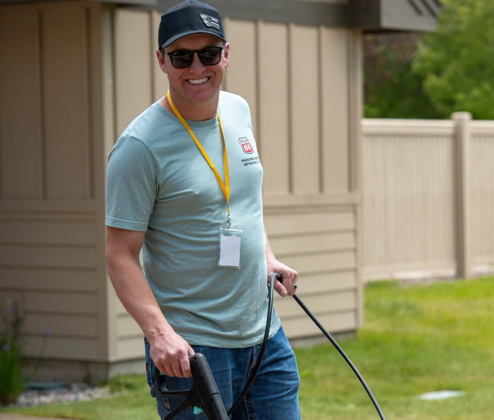 adult male smiling as he power washes a walkway