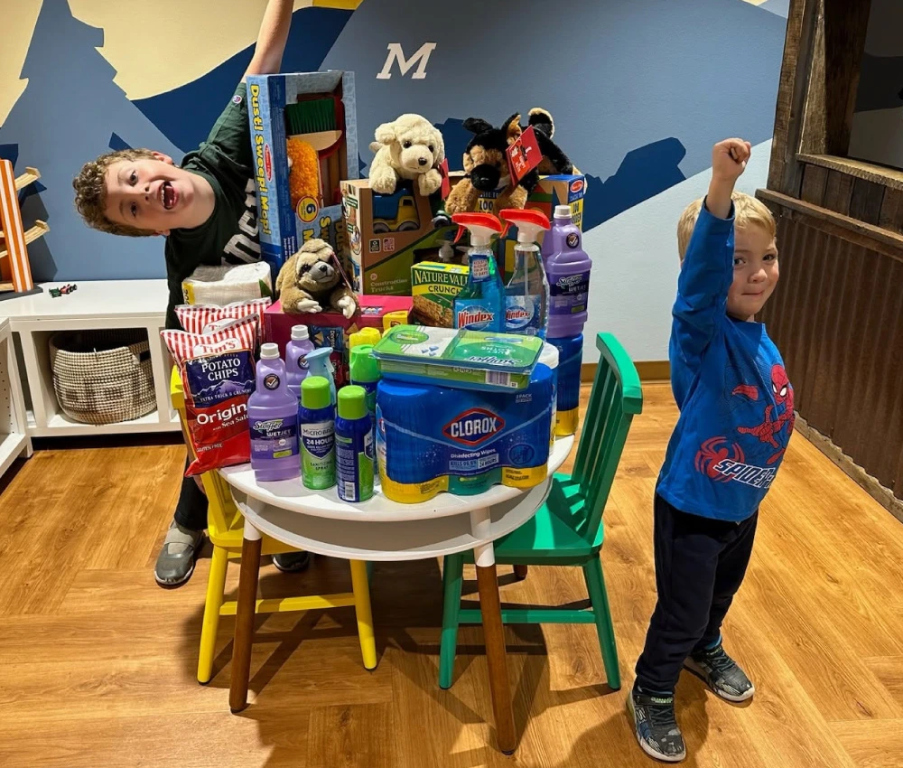 two young boys next to a table full of donated goods