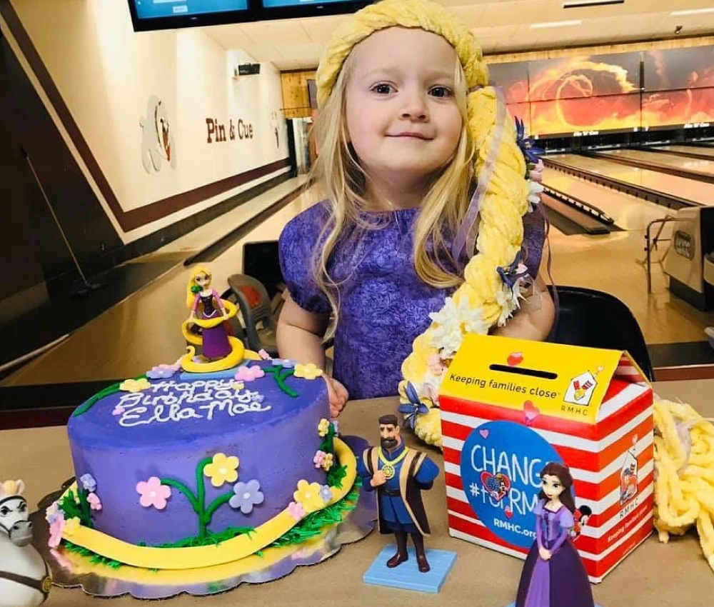 young girl with a birthday cake and a fundraising donation box for the Ronald McDonald House of Missoula